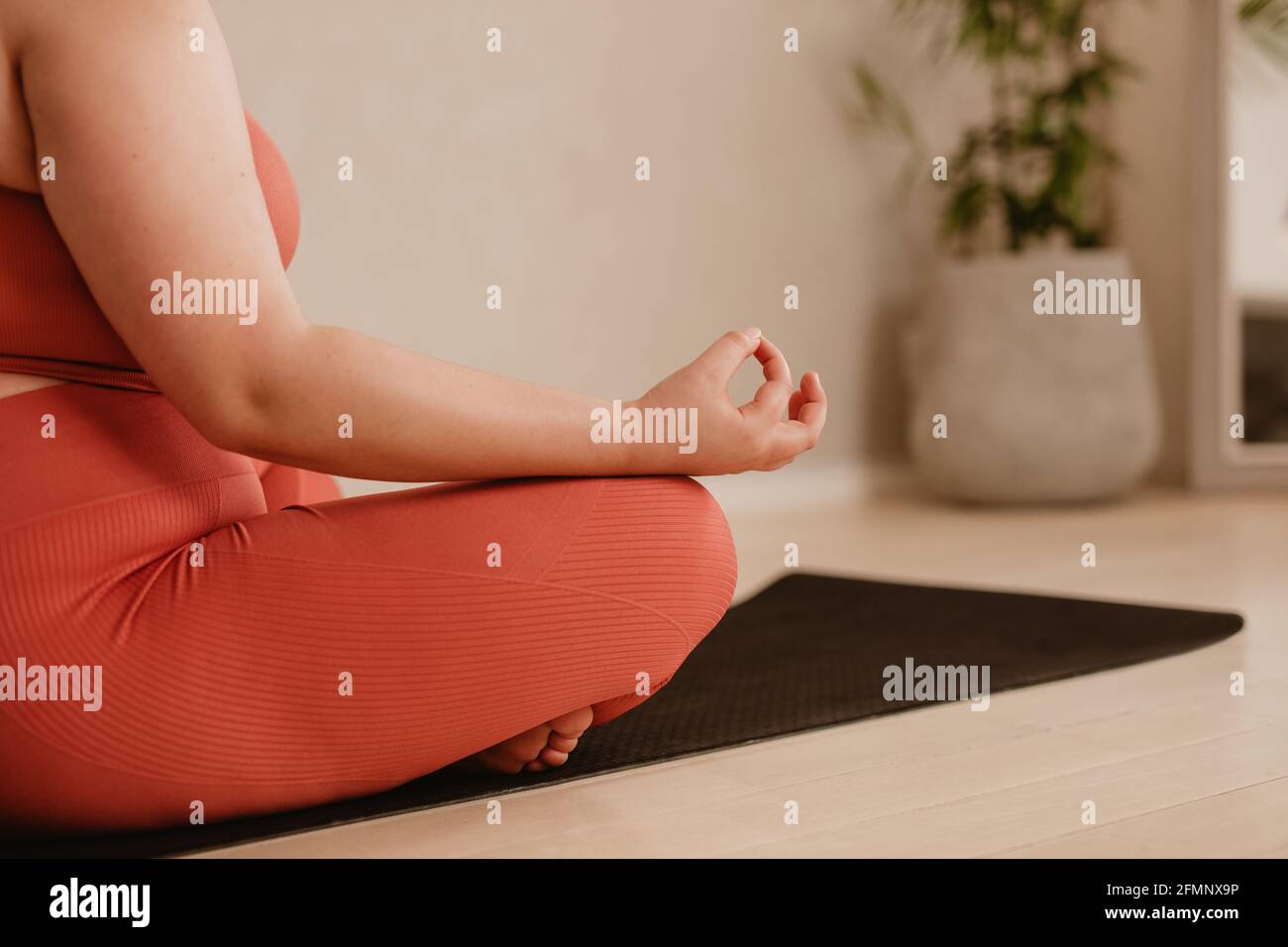 Ripresa di una donna che va meditazione yoga in palestra fitness. Donna seduta con gambe incrociate e mano sul ginocchio, meditando in posa di loto. Foto Stock