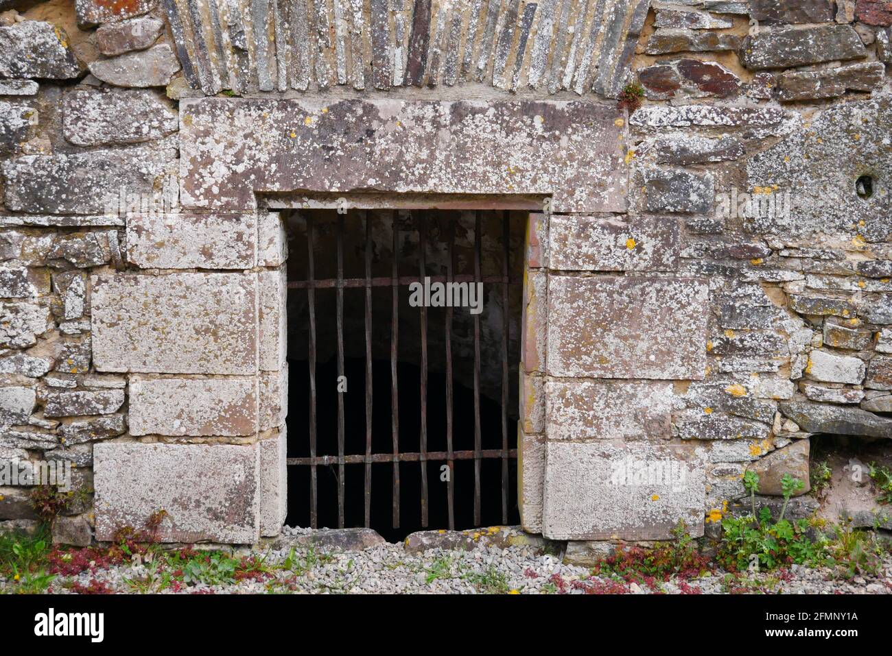 Barred ingresso a una prigione nella parete medievale di un vecchio castello rovina Foto Stock