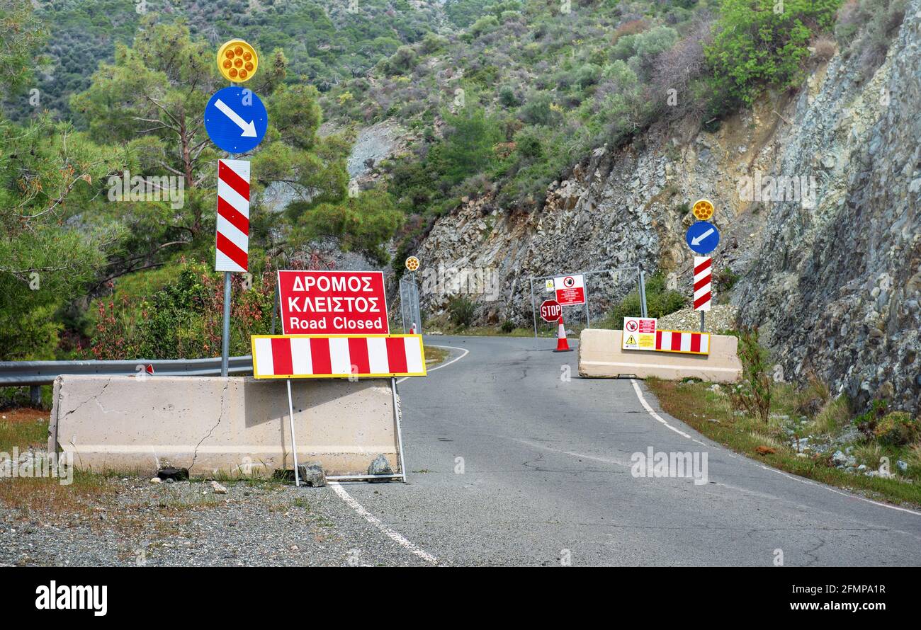 Strada in riparazione in Troodos montagne, Cipro. Stop e strada chiuse cartelli in inglese e greco Foto Stock