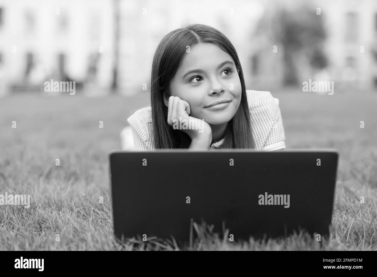 sognare il bambino rilassarsi al notebook su erba verde nel parco e studiare online istruzione scolastica, relax Foto Stock