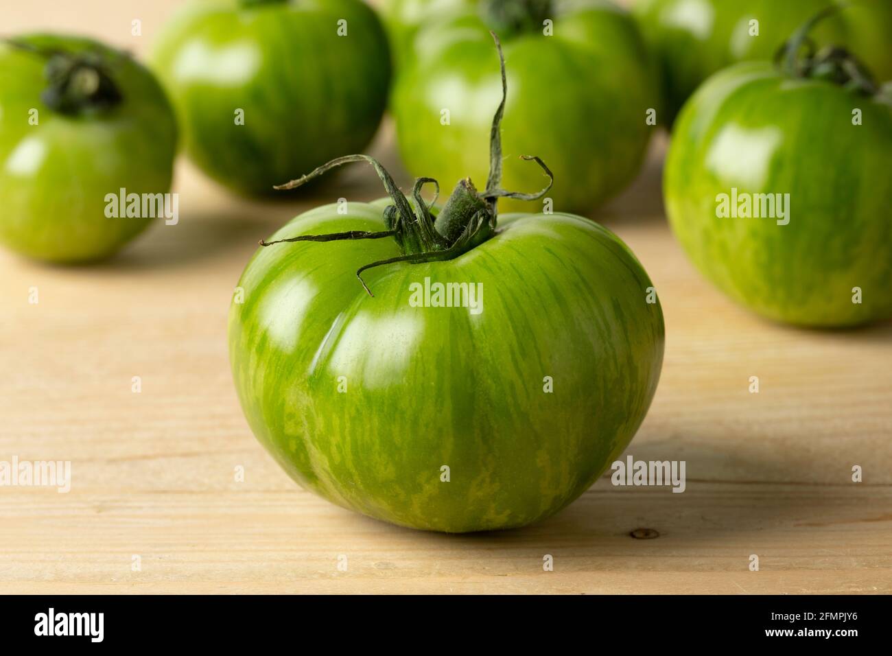 Primo piano di pomodoro verde zebra intero e pomodori in lo sfondo Foto Stock