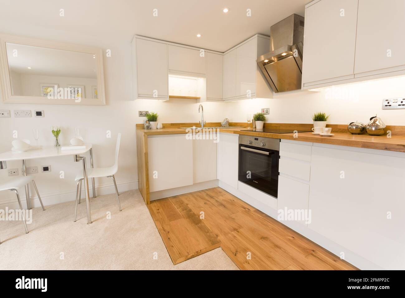 Un moderno appartamento cucina con ripiani in legno tavolo armadio ed elettrodomestici da cucina Foto Stock