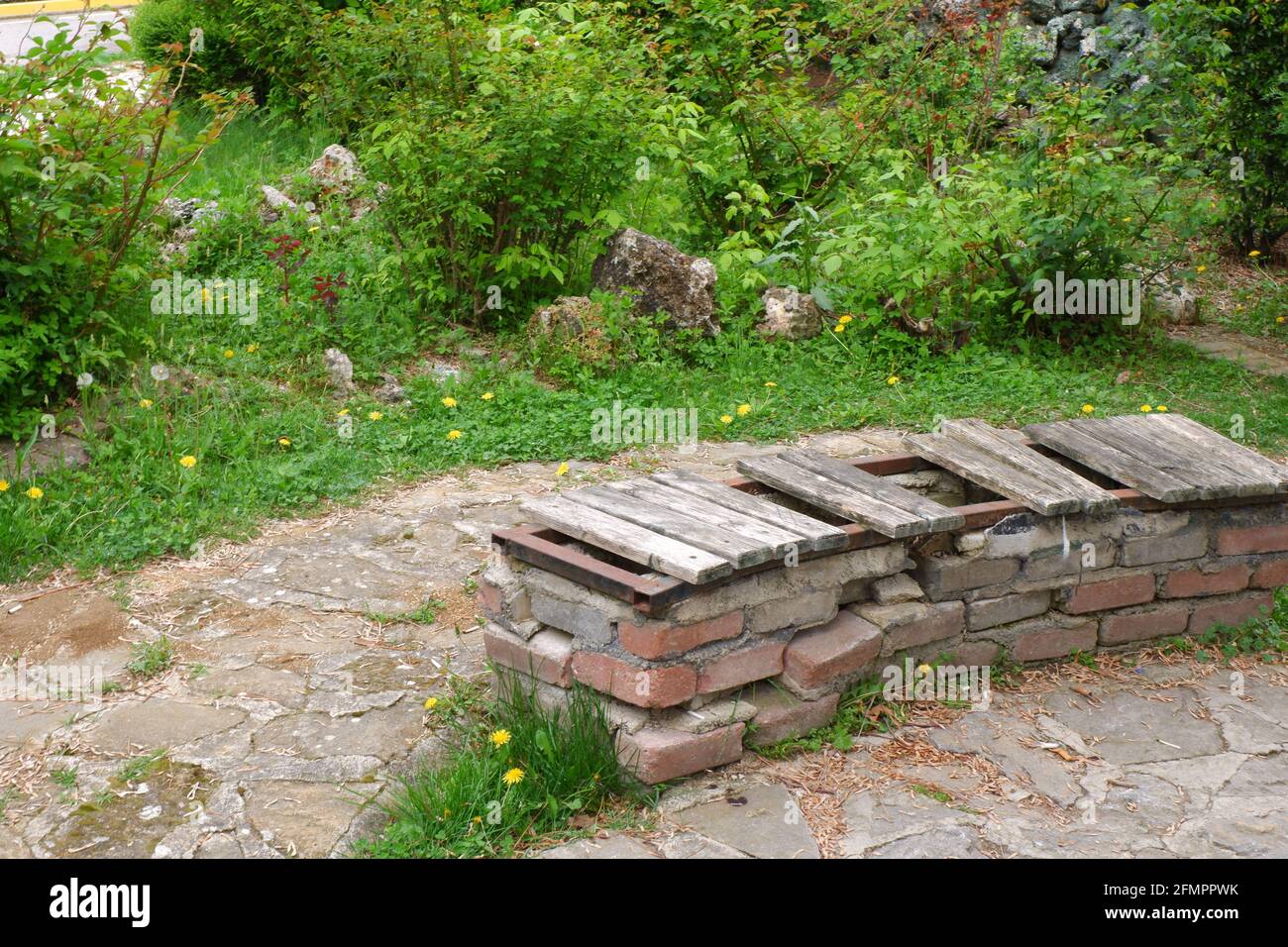 Vecchio panca fatto di mattoni con parti di legno perse a. parcheggio Foto Stock