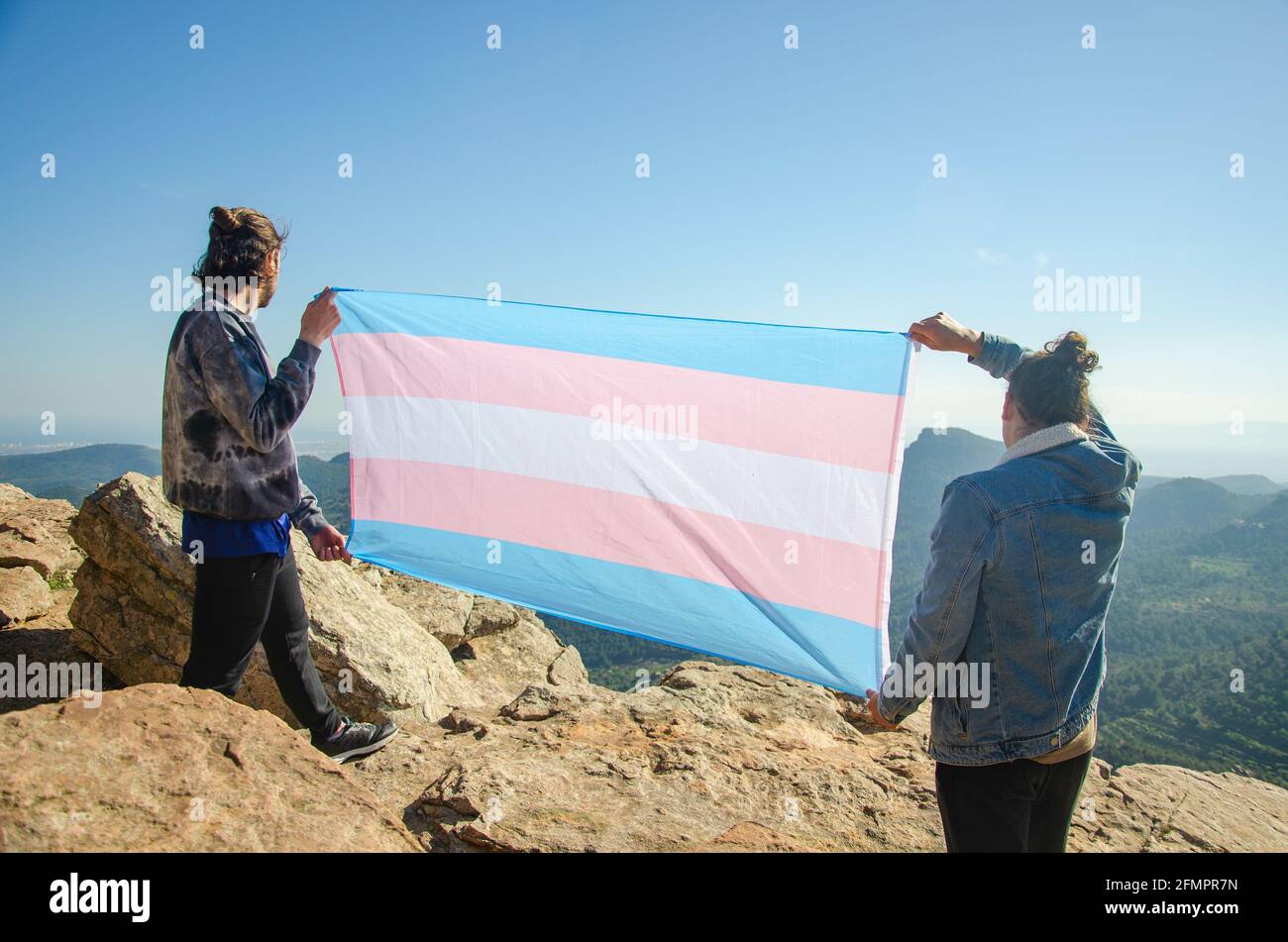 Attivista transgender uomini in vista posteriore mostrando con orgoglioso LGTB Bandiera Trans Blu e Rosa al mountà Foto Stock