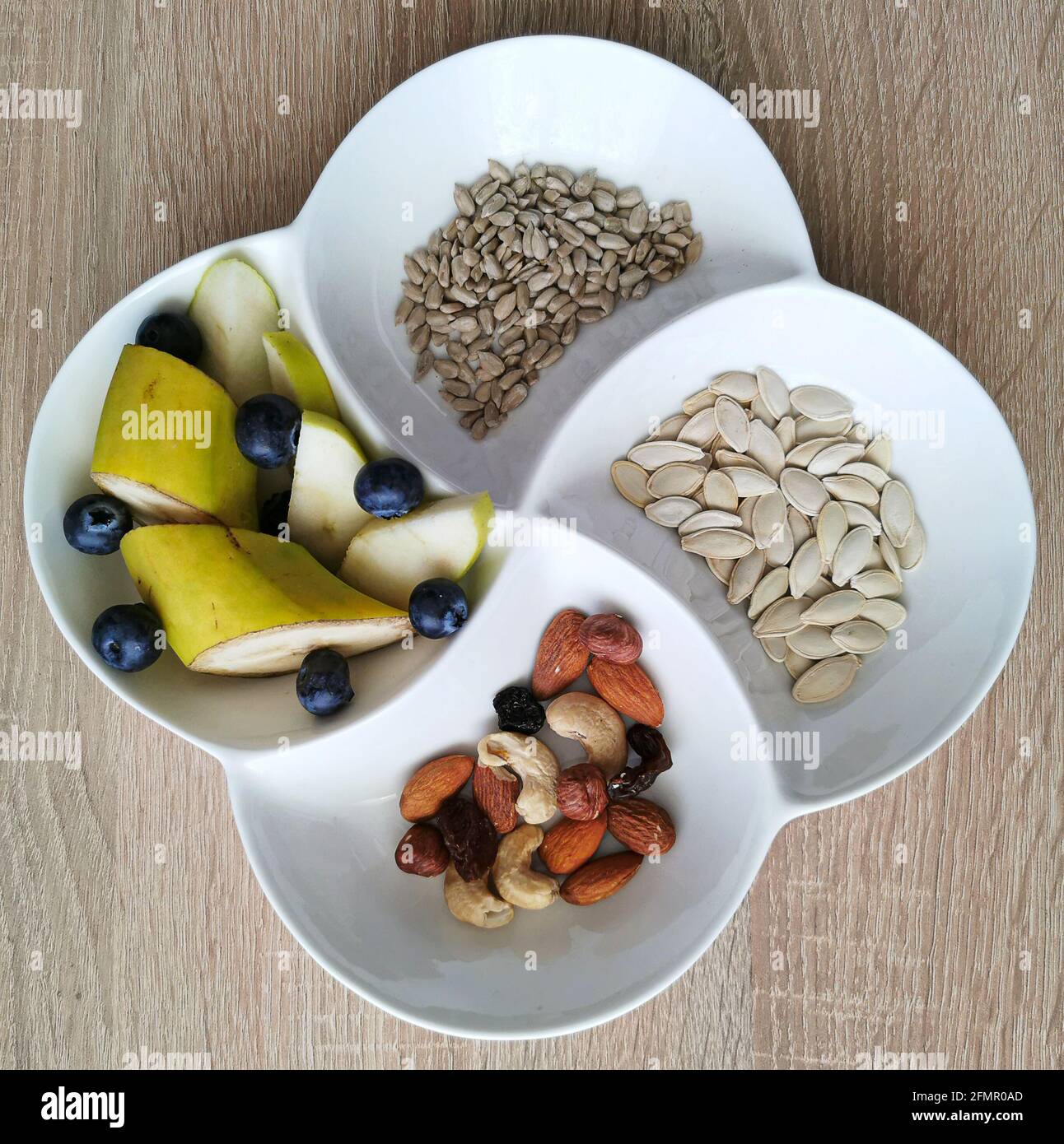 Uno spuntino sano. Noci, girasole e semi di zucca. Pezzi di banana, mele e mirtilli Foto Stock