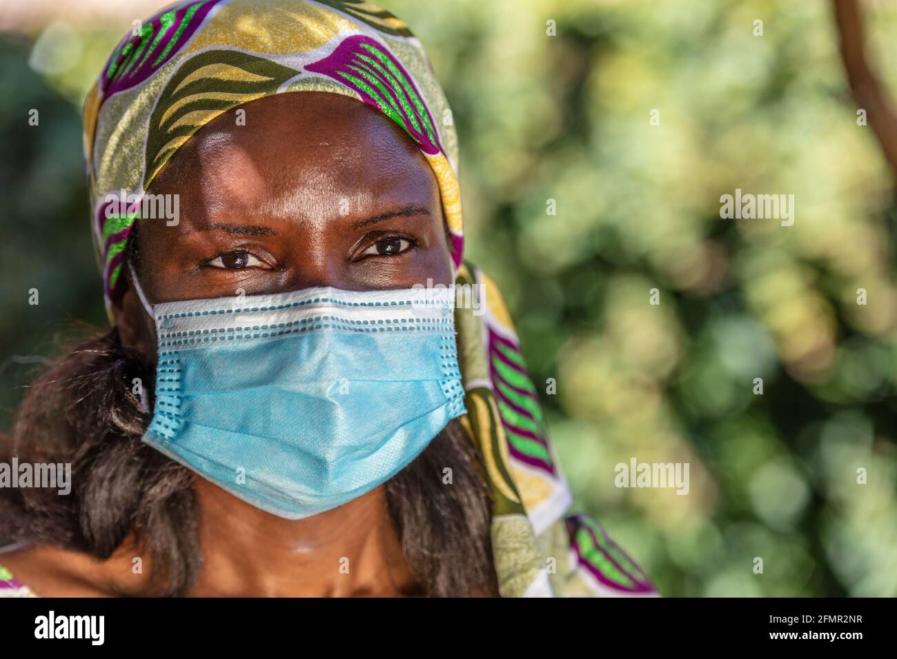 Donna africana di mezza età, donna in Africa, con abiti tradizionali e maschera facciale in pandemia di Coronavirus COVID-19 Foto Stock