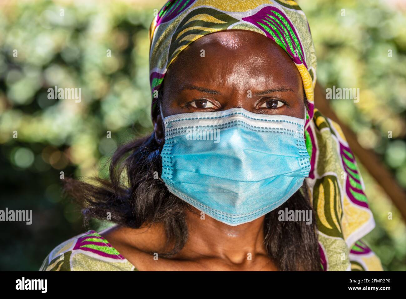 Donna africana di mezza età, donna in Africa, con abiti tradizionali e maschera facciale in pandemia di Coronavirus COVID-19 Foto Stock