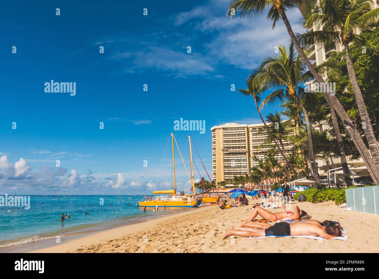 Oahu Hawaii persone godere Waikiki spiaggia con hotel e barca a vela sulla spiaggia Foto Stock