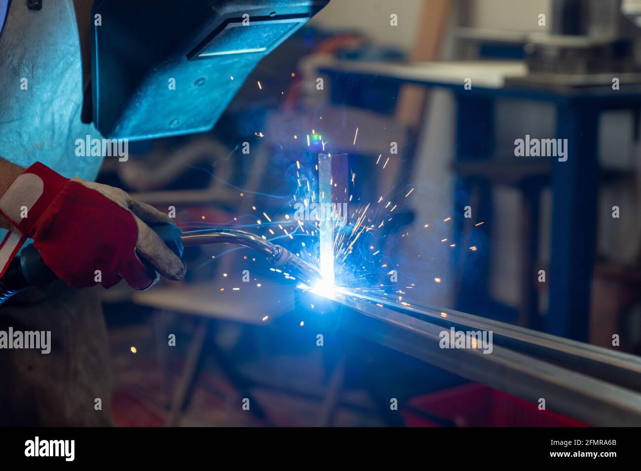 Un lavoratore di metallo che salda e costruisce un telaio di metallo per un patio giardino Foto Stock