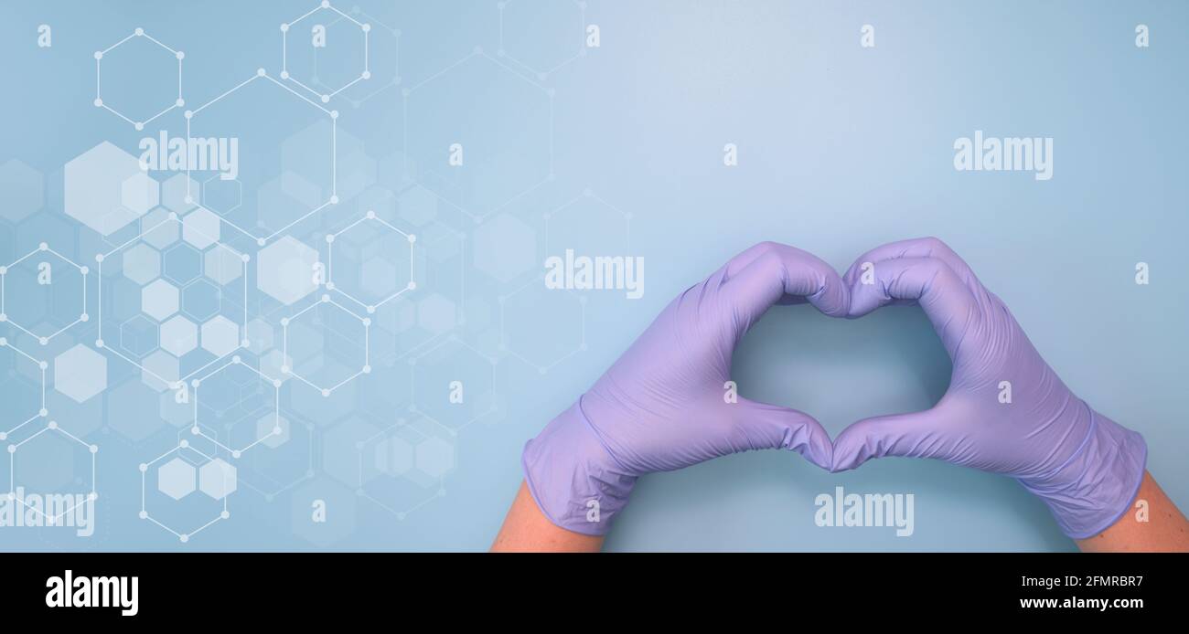 Mani del medico in guanti medici a forma di cuore su sfondo blu. Banner per sito Web con spazio per la copia. Foto Stock