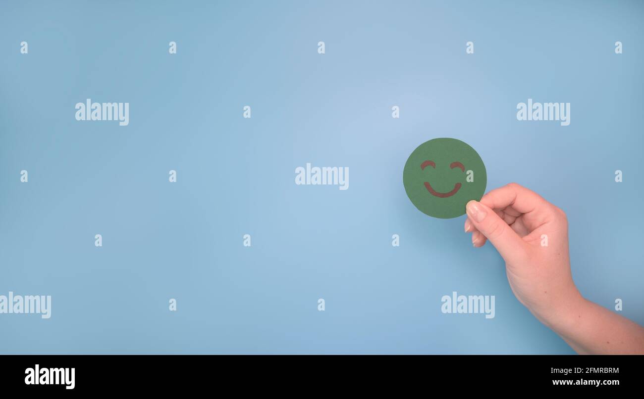Mano scelta carta verde taglio felice sorriso faccia. Feedback, valutazione e valutazione positiva del cliente, esperienza, sondaggio sulla soddisfazione Foto Stock