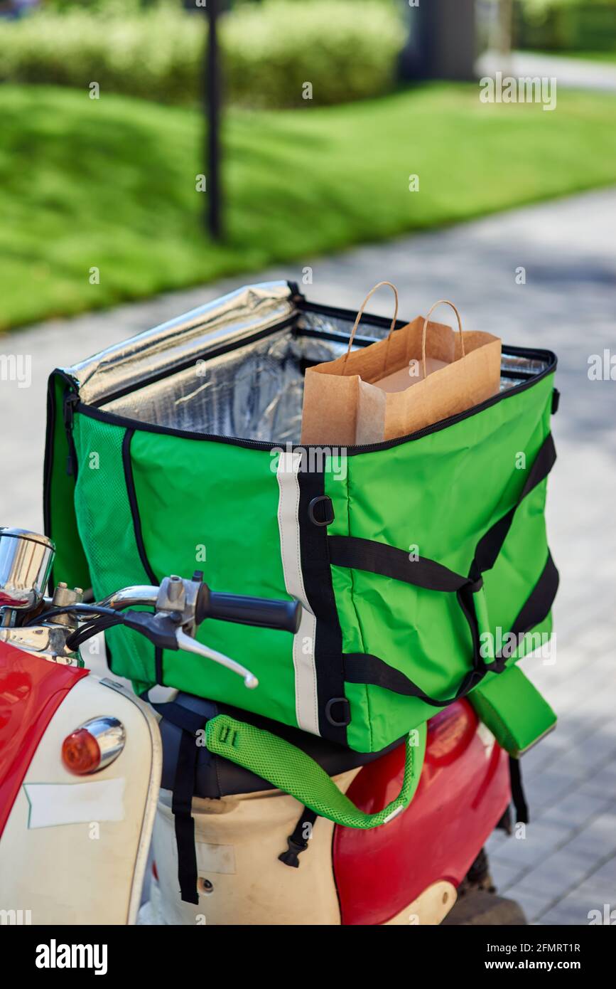 Consegna del cibo dal ristorante alla porta. Zaino termico verde con borsa  di carta su scooter all'aperto Foto stock - Alamy