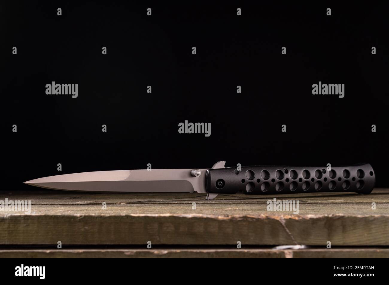 Un coltello grande e affilato che giace su una scatola militare. Una lama di coltello sotto forma di lancia. Vista frontale. Foto Stock