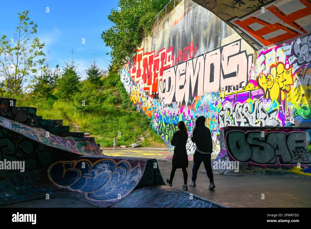 Coppia che cammina attraverso graffiti coperti, Leeside Tunnel Skateboard Park, East Vancouver, British Columbia, Canada Foto Stock