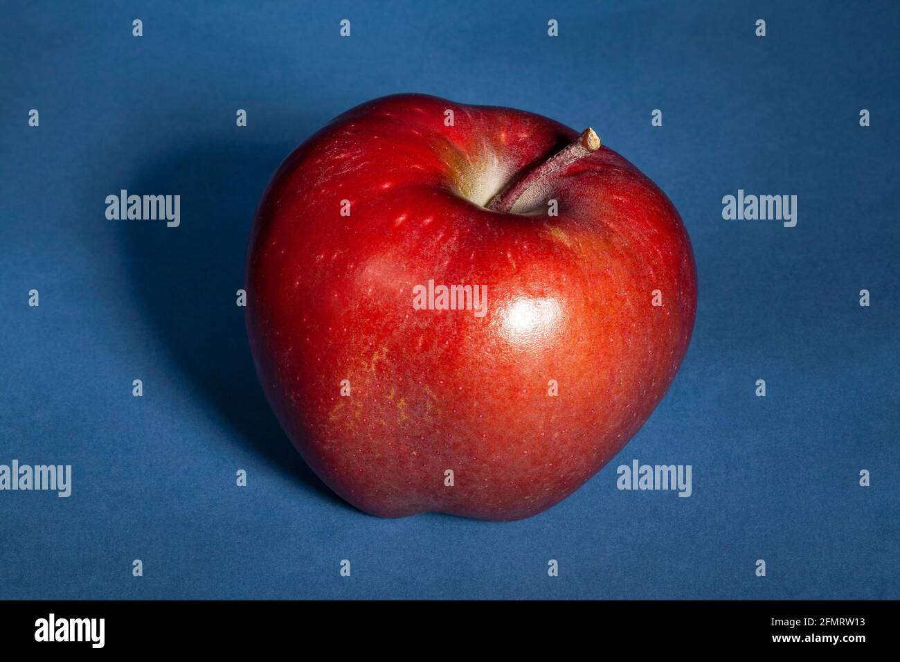 mela rossa deliziosa su sfondo blu Foto Stock