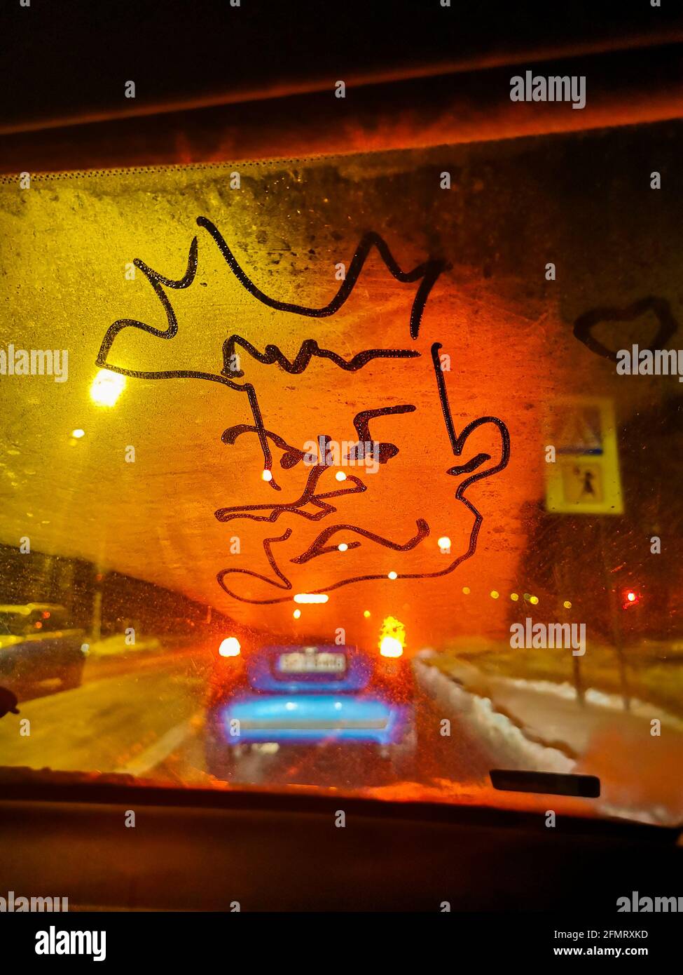 Disegno sulla finestra di un'auto, vista verticale, semafori di notte, strade innevate invernali Foto Stock