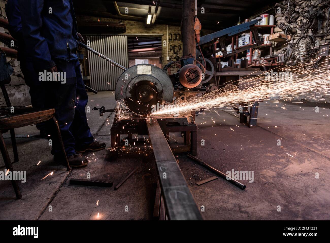 Un lavoratore di metallo su una fattoria sudafricana di Karoo taglio acciaio con smerigliatrice angolare per montanti di recinzione Foto Stock