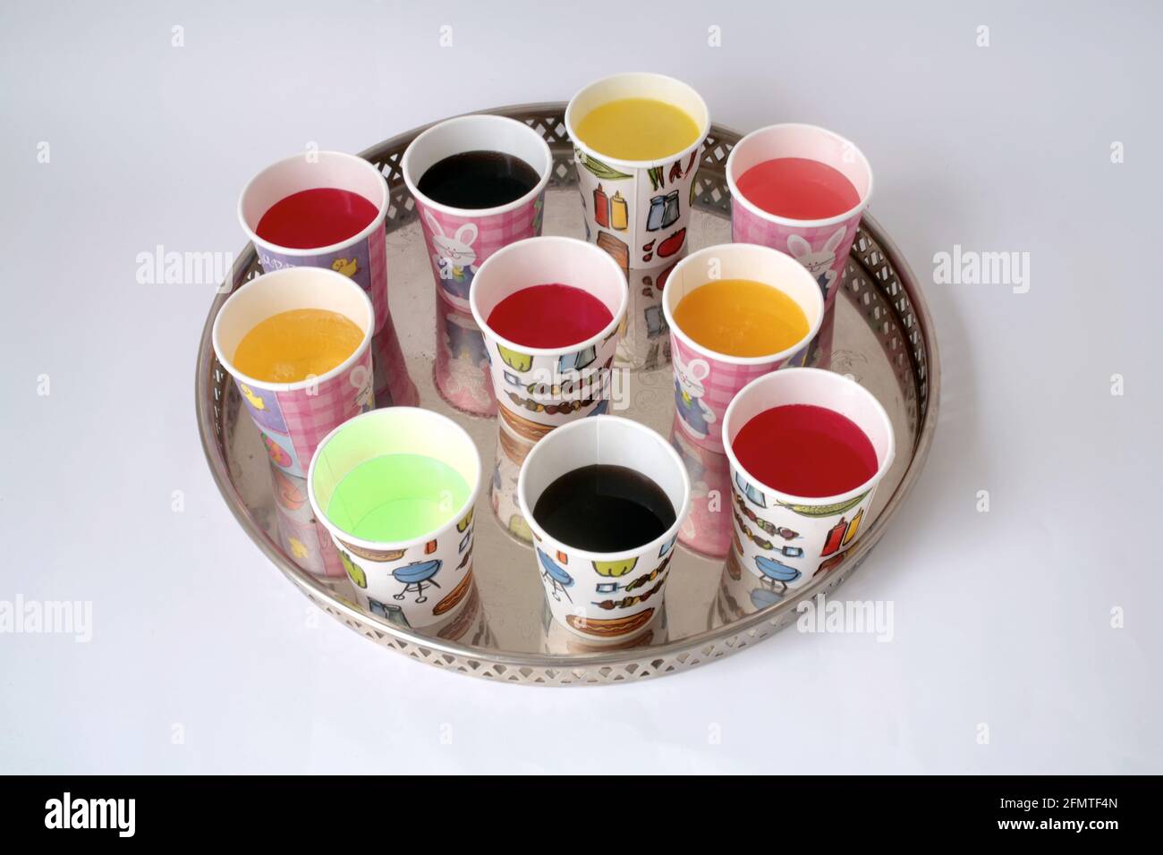 Succhi colorati in tazze di carta su vassoio circolare in argento Foto Stock