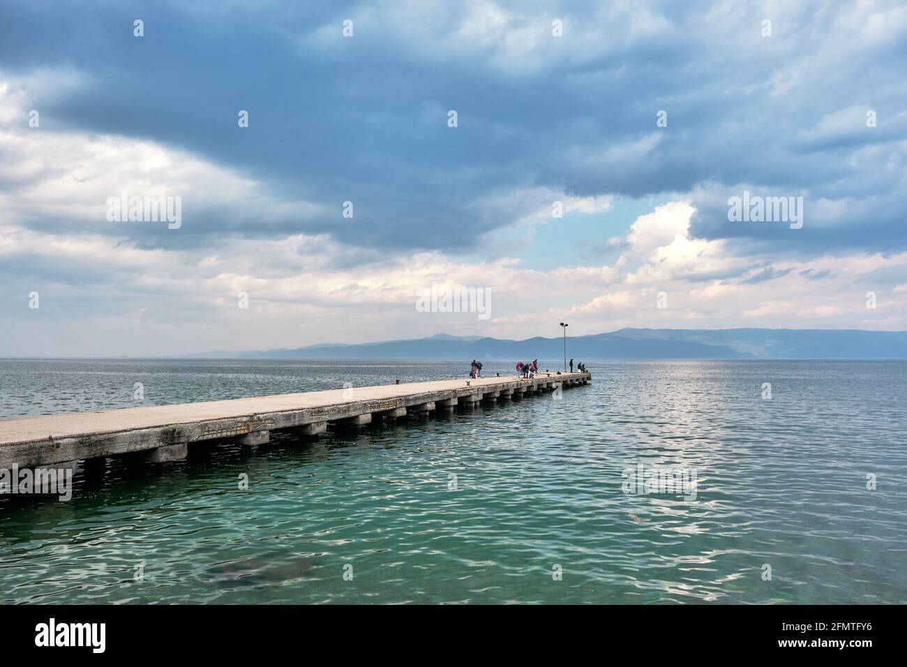 Molte persone che pescano sul molo e il porto si estende al mare di marmara durante il tempo sovrastato e la giornata delle piogge. Sole che arriva dopo le nuvole. Foto Stock