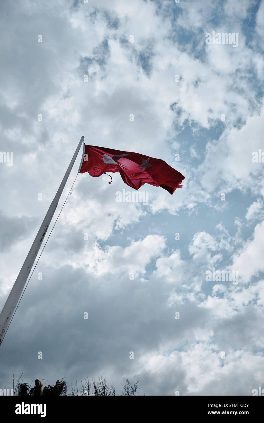 Enorme bandiera turca con sfondo cielo nuvoloso sovrastato. La bandiera è lacerata Foto Stock