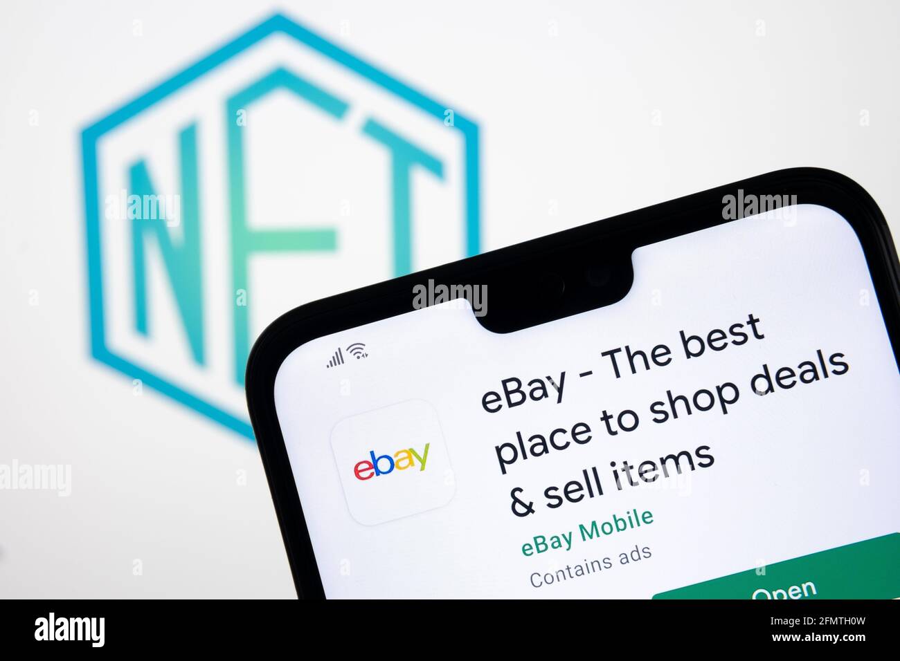 Concetto di NFT EBAY. App eBay visualizzata sullo smartphone e logo del token non fungibile sfocato sullo schermo del laptop con sfondo sfocato. Stafford, Regno Unito Foto Stock