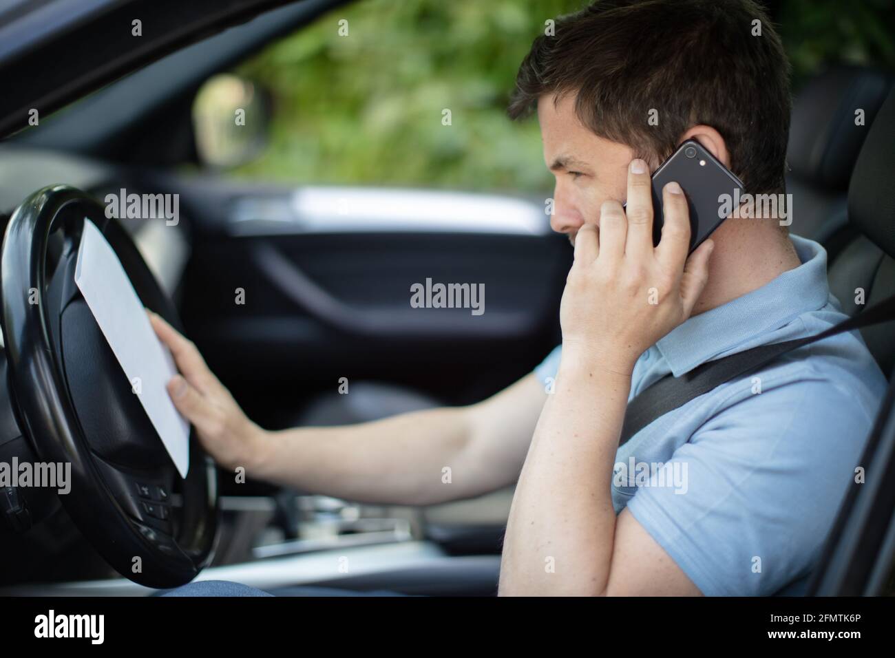 uomo che parla al telefono mentre guida la sua auto Foto Stock
