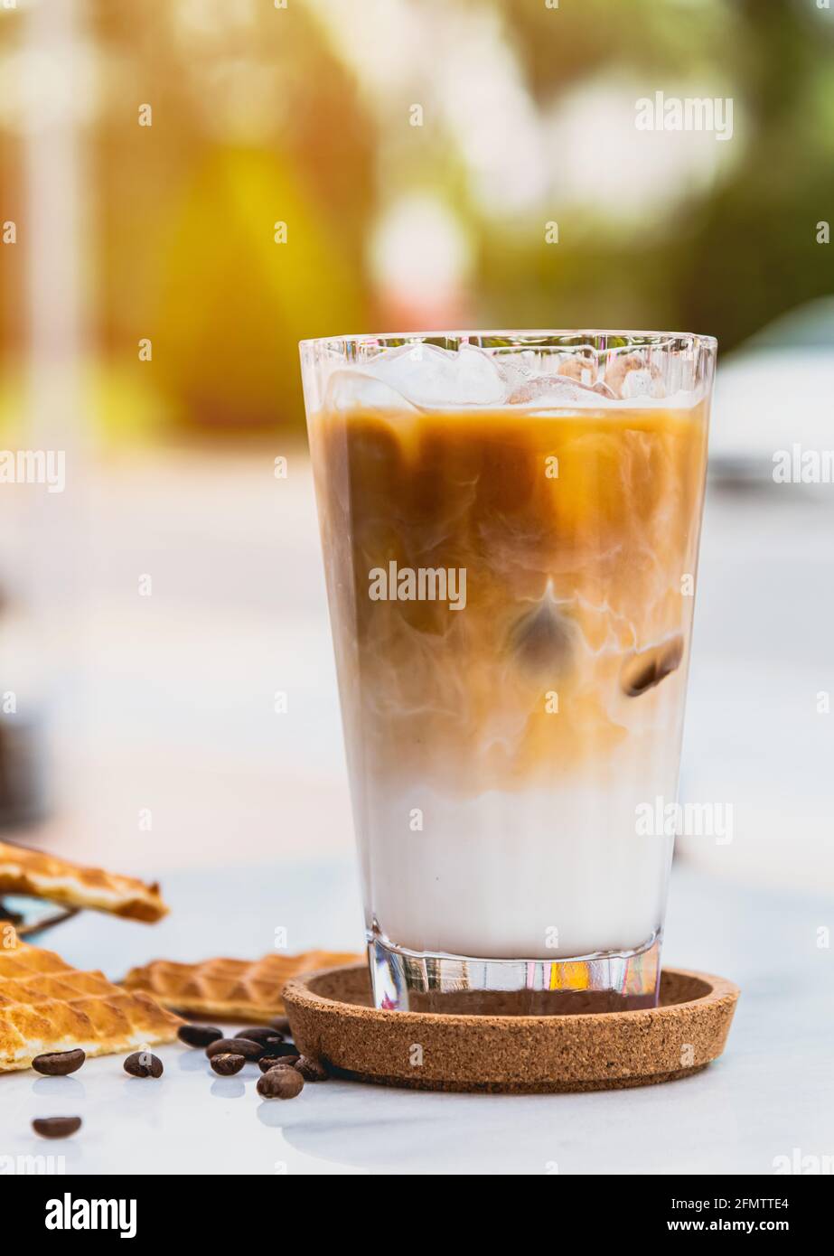 Caffè latte ghiacciato rinfrescante in un bicchiere con waffle a cuore e chicchi di caffè Foto Stock