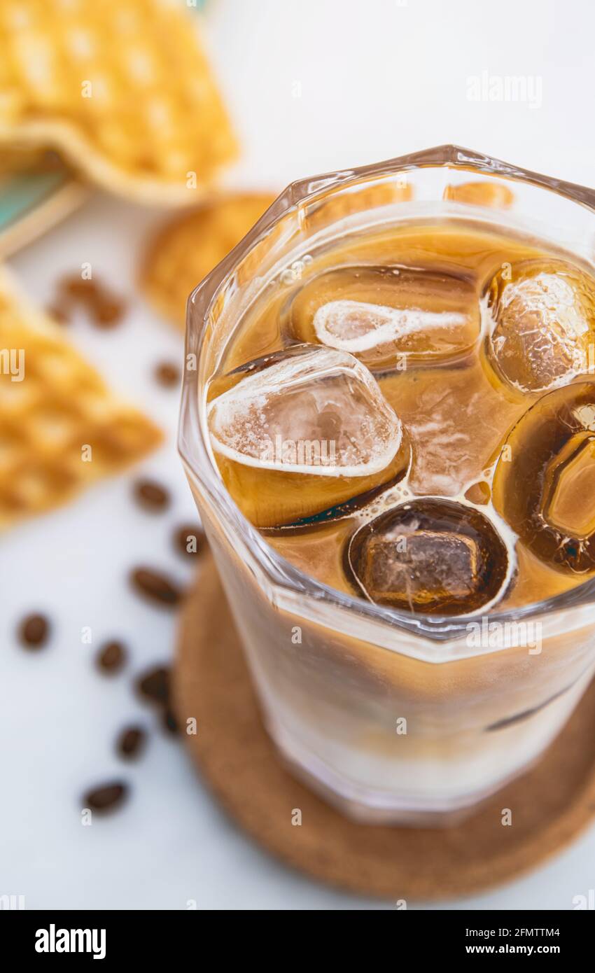 Caffè latte ghiacciato rinfrescante in un bicchiere con waffle a cuore e chicchi di caffè Foto Stock