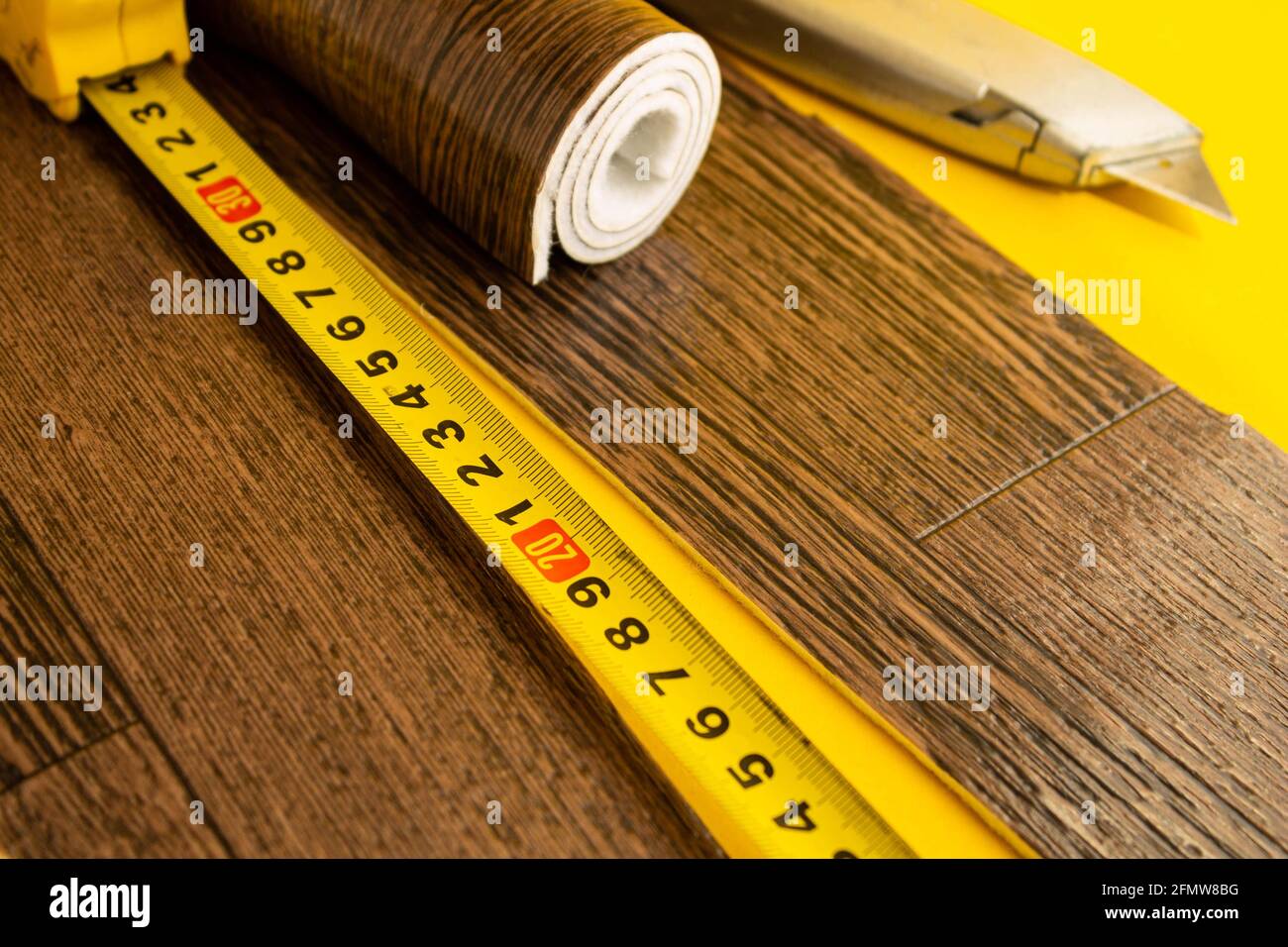 Metro a nastro in linoleum e coltello su fondo isolato. Un pezzo di linoleum. Misurazione e taglio del linoleum. Linoleum per pavimenti in PVC. Galleggiamento domestico Foto Stock
