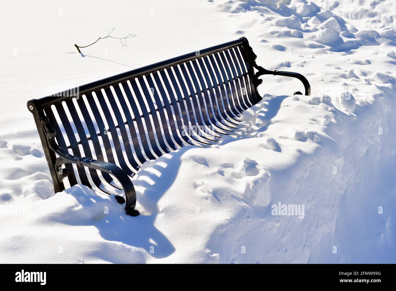 Itasca, Illinois, Stati Uniti. Una panchina del parco isolata da una nevicata accumulata in una luminosa e soleggiata mattina d'inverno. Foto Stock