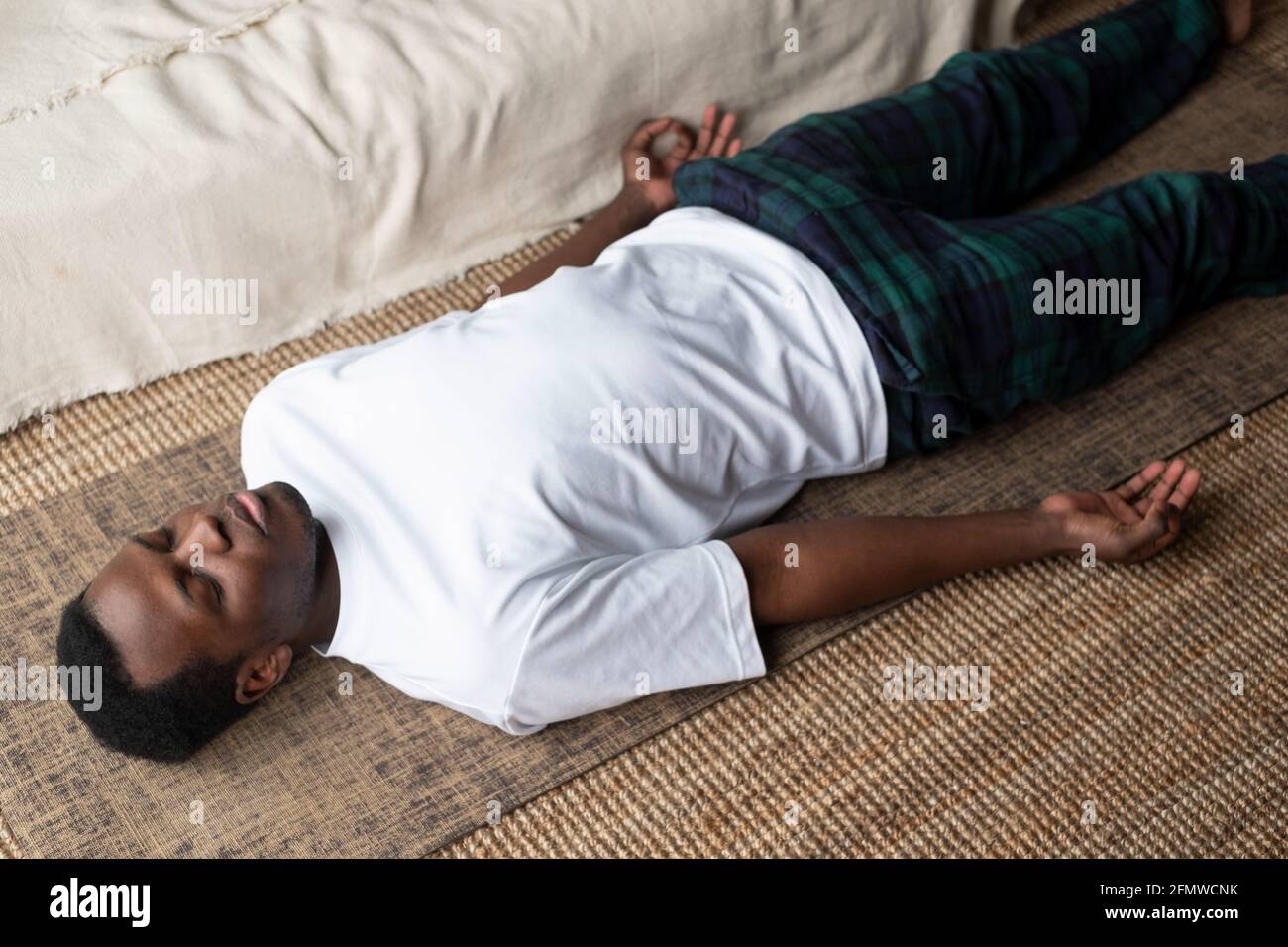 Giovane uomo nero sdraiato in Dead Body esercizio o Corpse posa con gli occhi chiusi, Savasana posa Foto Stock