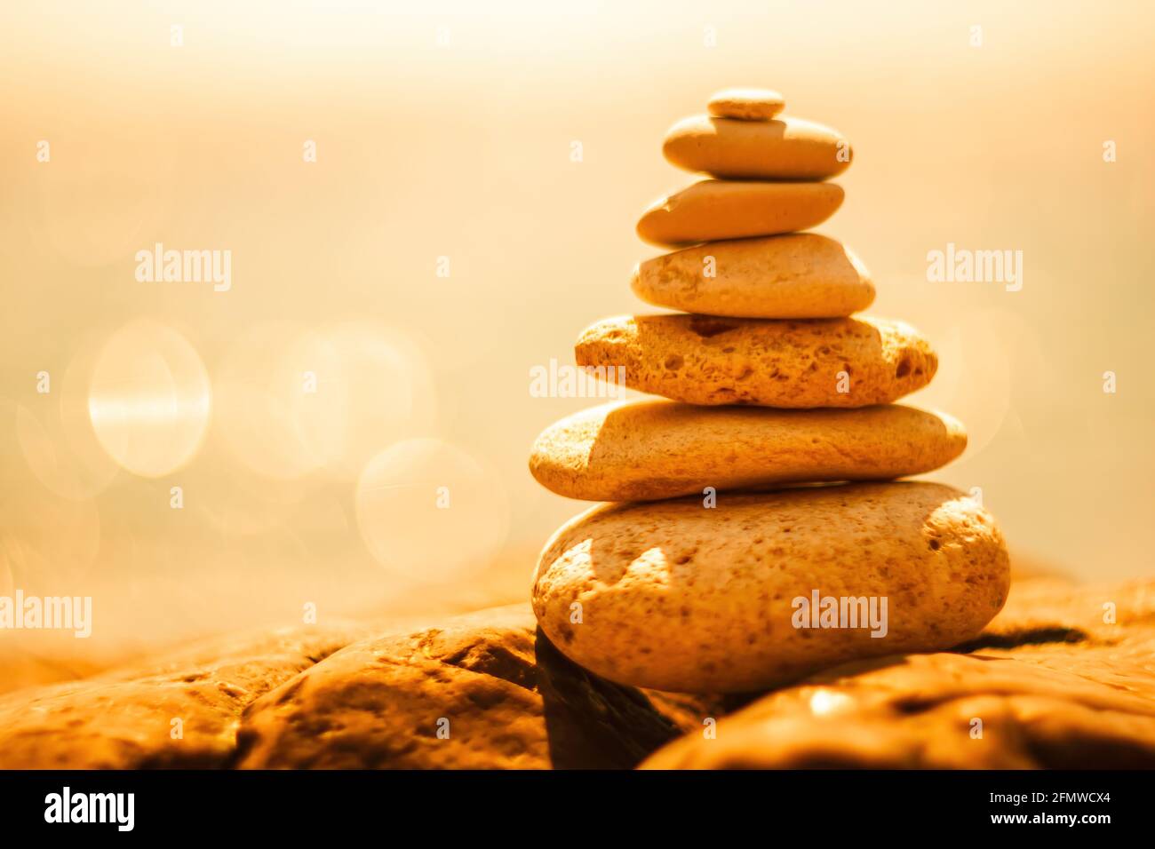 Equilibrata piramide di ciottoli sulla spiaggia in una giornata di sole. Abstract Sea bokeh sullo sfondo. Messa a fuoco selettiva. Pietre Zen sulla spiaggia di mare, meditazione Foto Stock