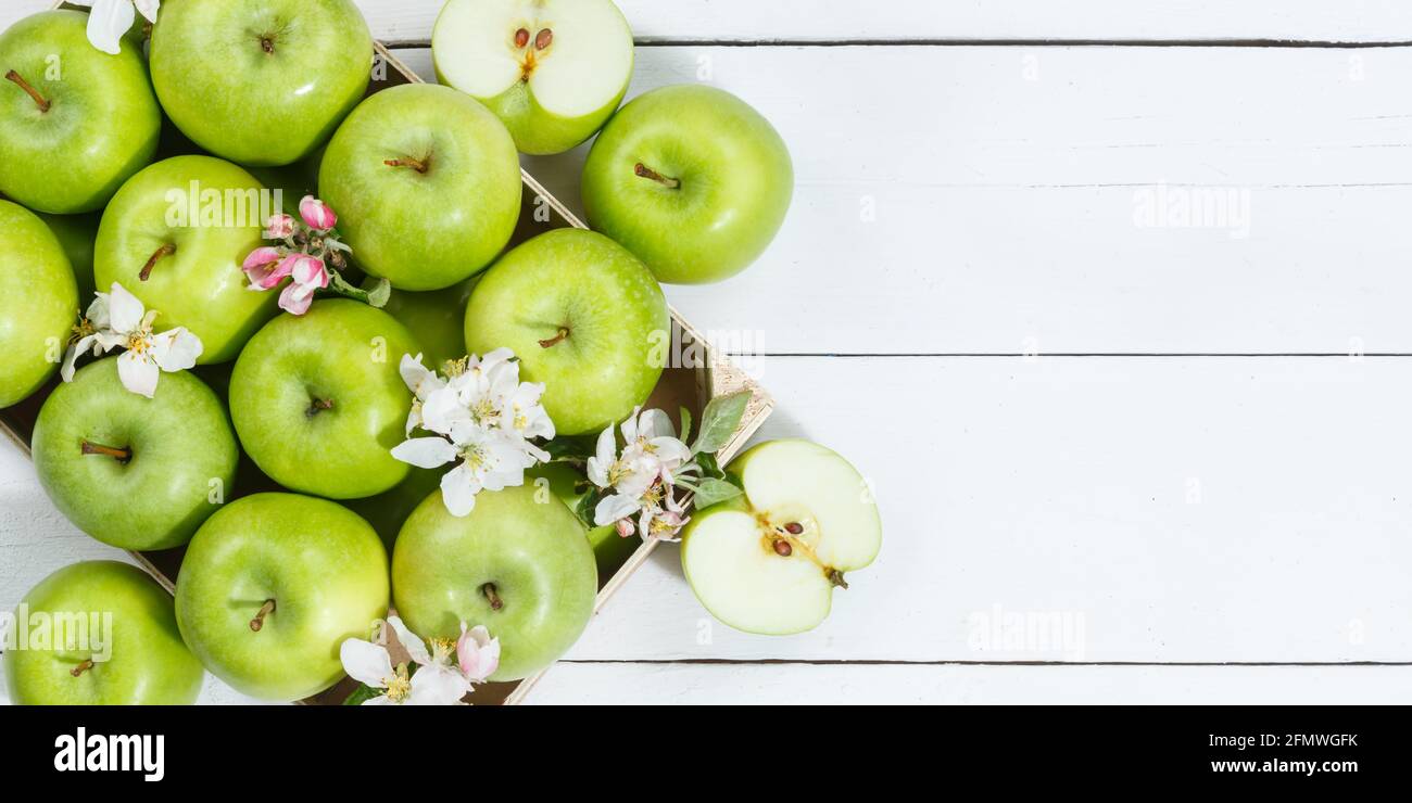 Stoccarda, Germania - 29. Aprile 2021: Äpfel Früchte grün Apfel Frucht Kiste auf Holzbrett Banner Textfreiraum CopySpace mit Blüten und Blättern in Foto Stock