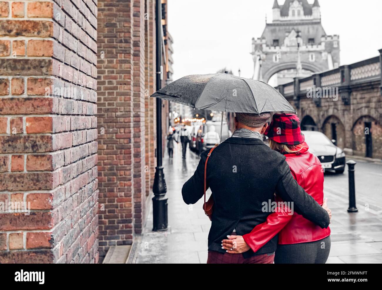 Coppia che cammina sotto la pioggia sotto un bellissimo Tower Bridge di Londra. Coppia in pensione che viaggia in tutto il mondo. Concetto di pensionato, amore e vacanza. Foto Stock