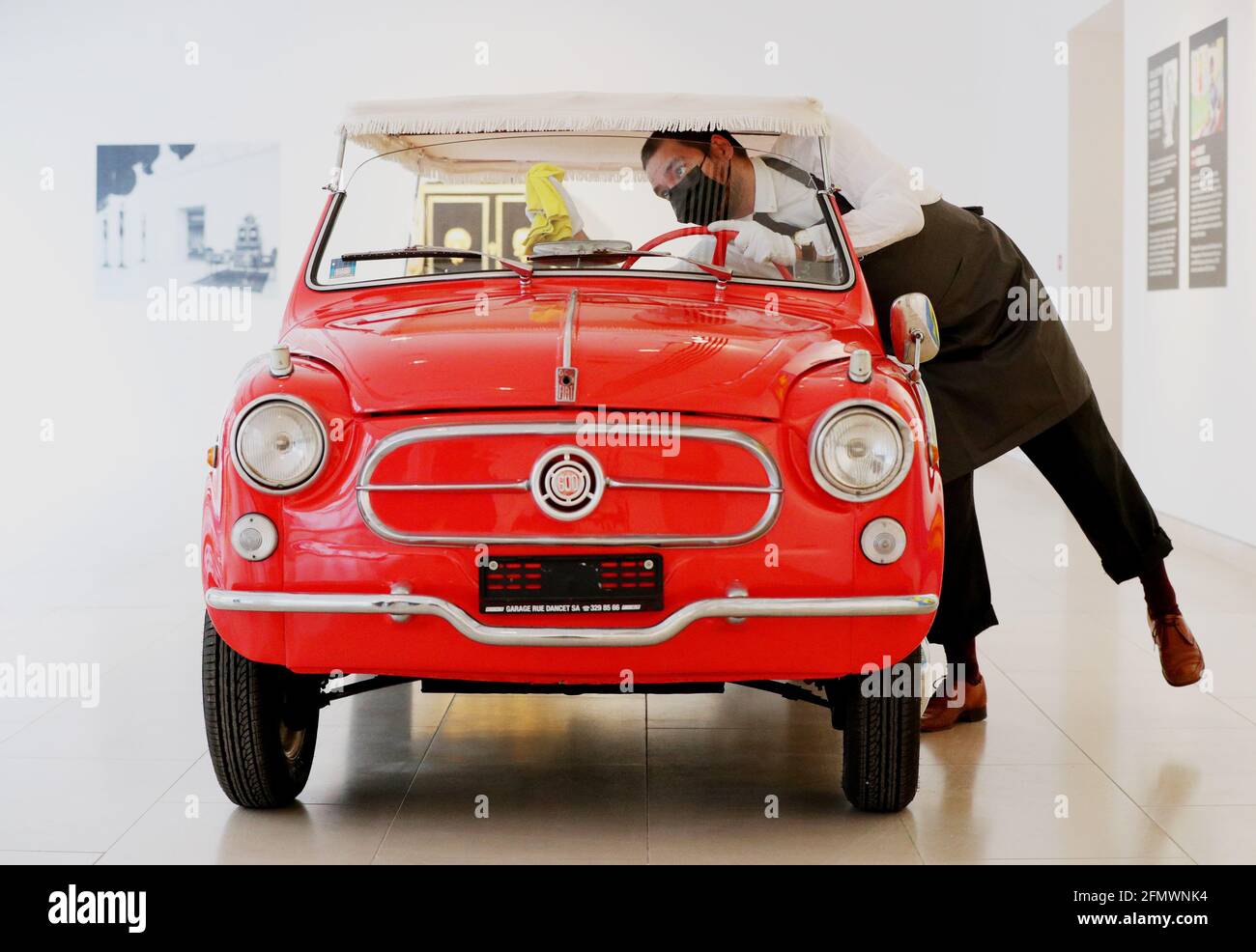 Un dipendente di Christie pulisce il parabrezza interno di una Fiat 600  Ghia "Beach Jolly" durante una telefonata per la prossima vendita a Londra  di "The Collection of Marion Lambert" presso la