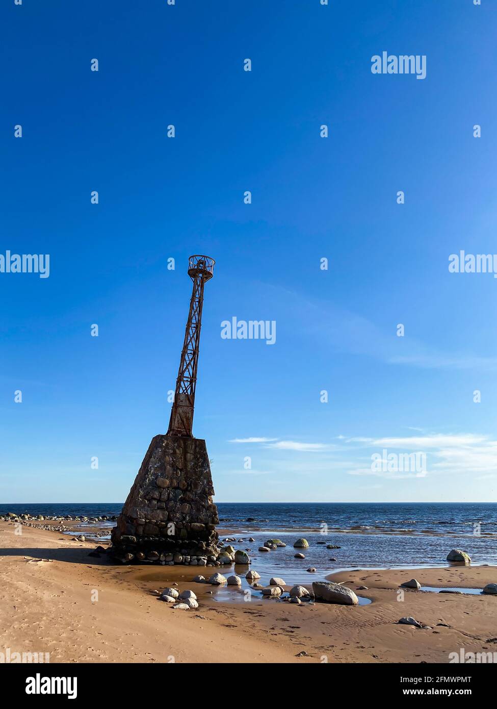 Bellissima spiaggia di mare con sabbia duna e un vecchio faro abbandonato. Il faro è basato su grandi pietre. Foto Stock