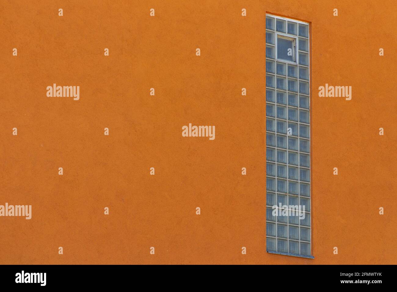 Finestra verticale costruita con blocchi di vetro in una parete arancione Foto Stock