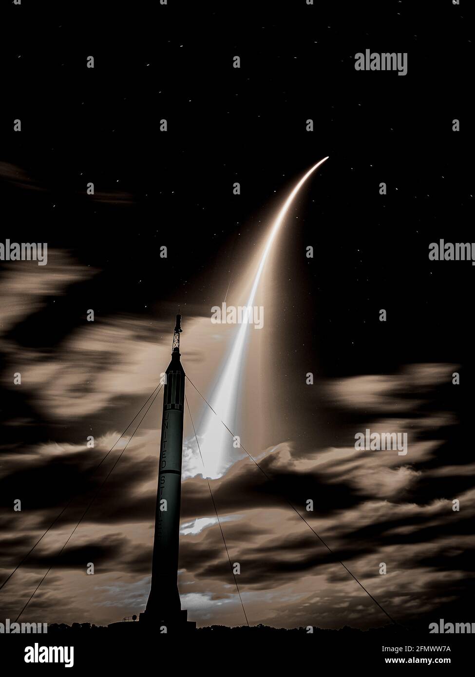Ripresa verticale di un lancio a razzo con luci di coda contro un cielo notturno nuvoloso Foto Stock