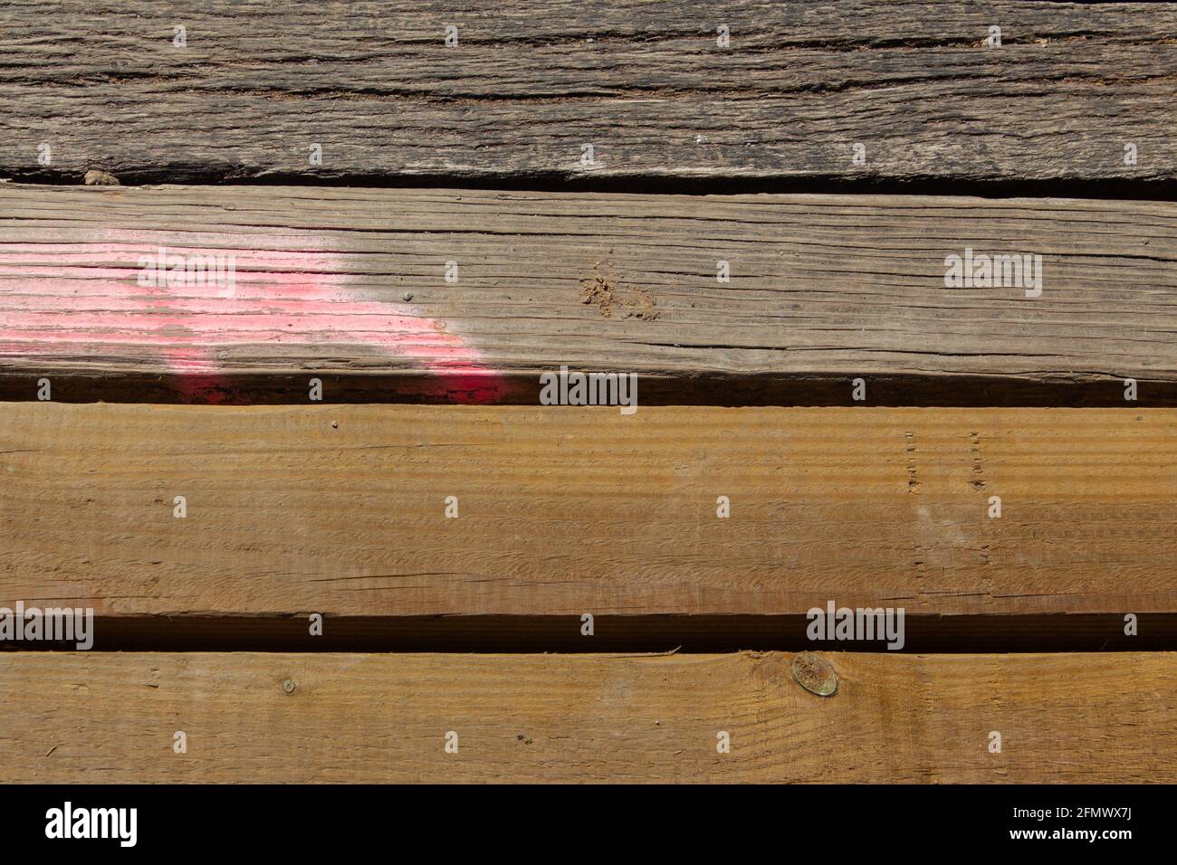 Tavole di legno danneggiate con segni rosa di vernice spray da contrassegnare come rinnovare Foto Stock