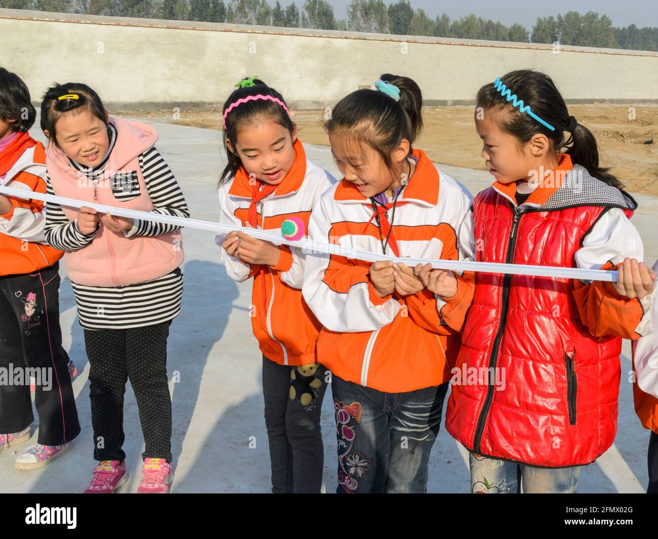 Gli studenti primari della Cina rurale lavorano insieme per passare la palla senza lasciarla cadere. Foto Stock