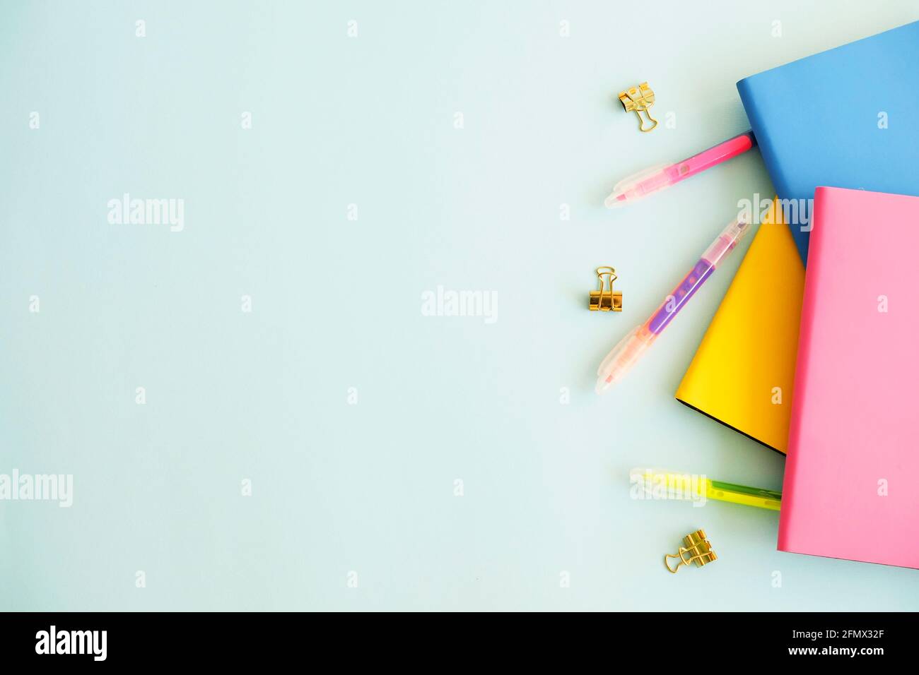 Set femminile di forniture scolastiche, copertina rosa gialla, taccuino a fogli bianchi, affilatrice a matita, penna colorata, leganti, adesivi e cancellatore, legno blu Foto Stock