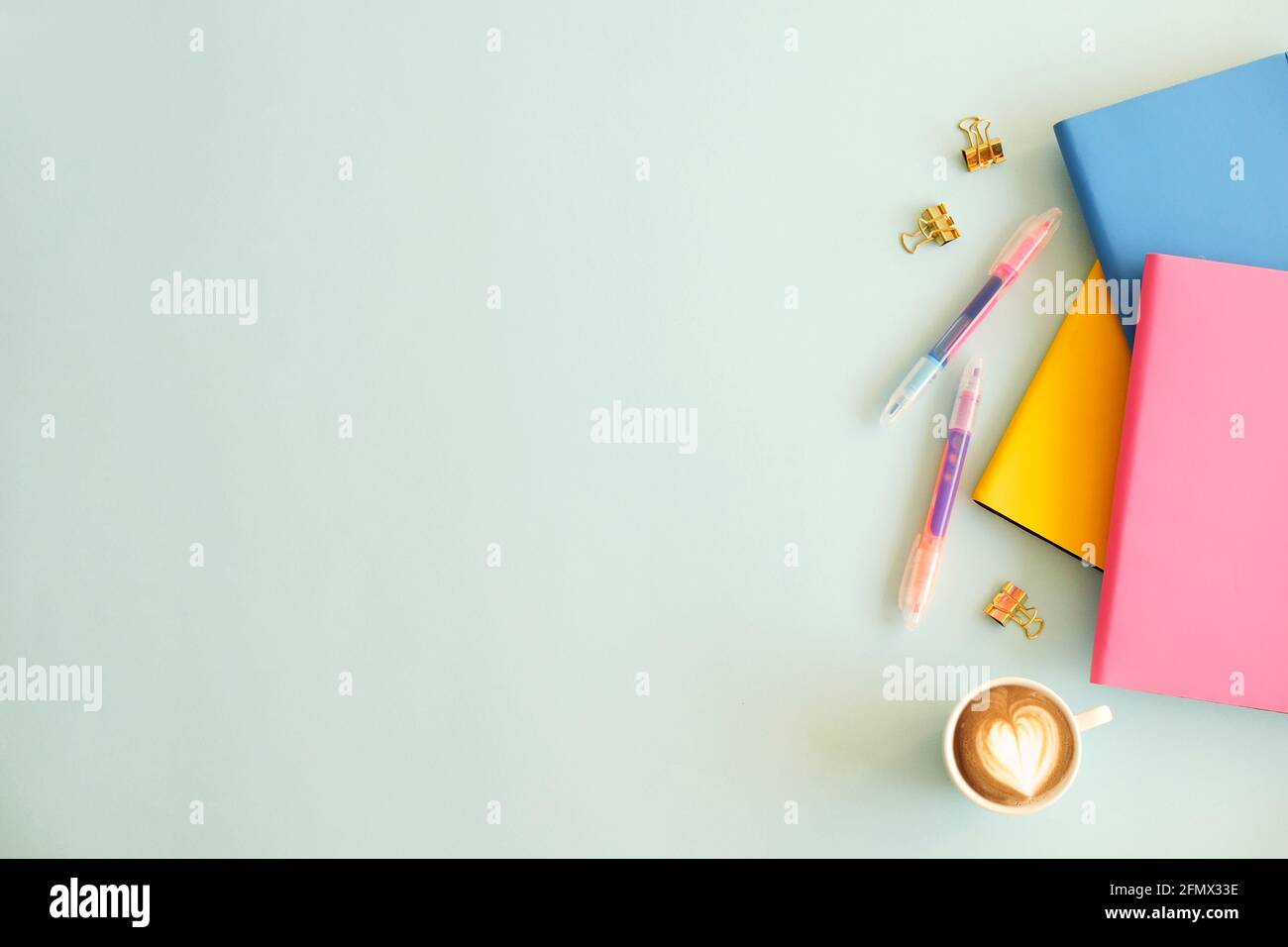 Set femminile di forniture scolastiche, copertina rosa gialla, taccuino a fogli bianchi, affilatrice a matita, penna colorata, leganti, adesivi e cancellatore, legno blu Foto Stock