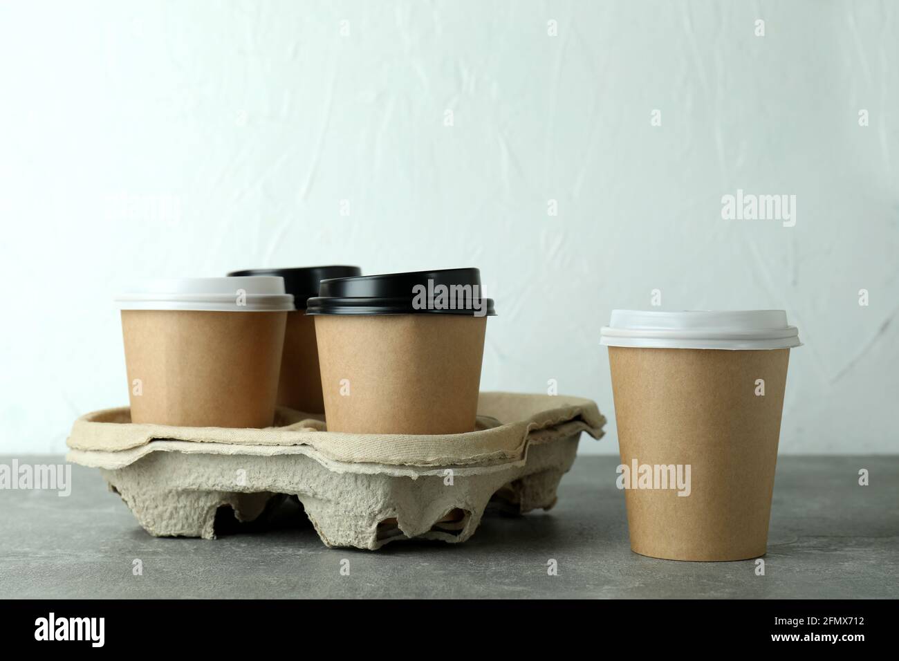 Portabicchieri con tazze da caffè su tavolo grigio con texture Foto Stock