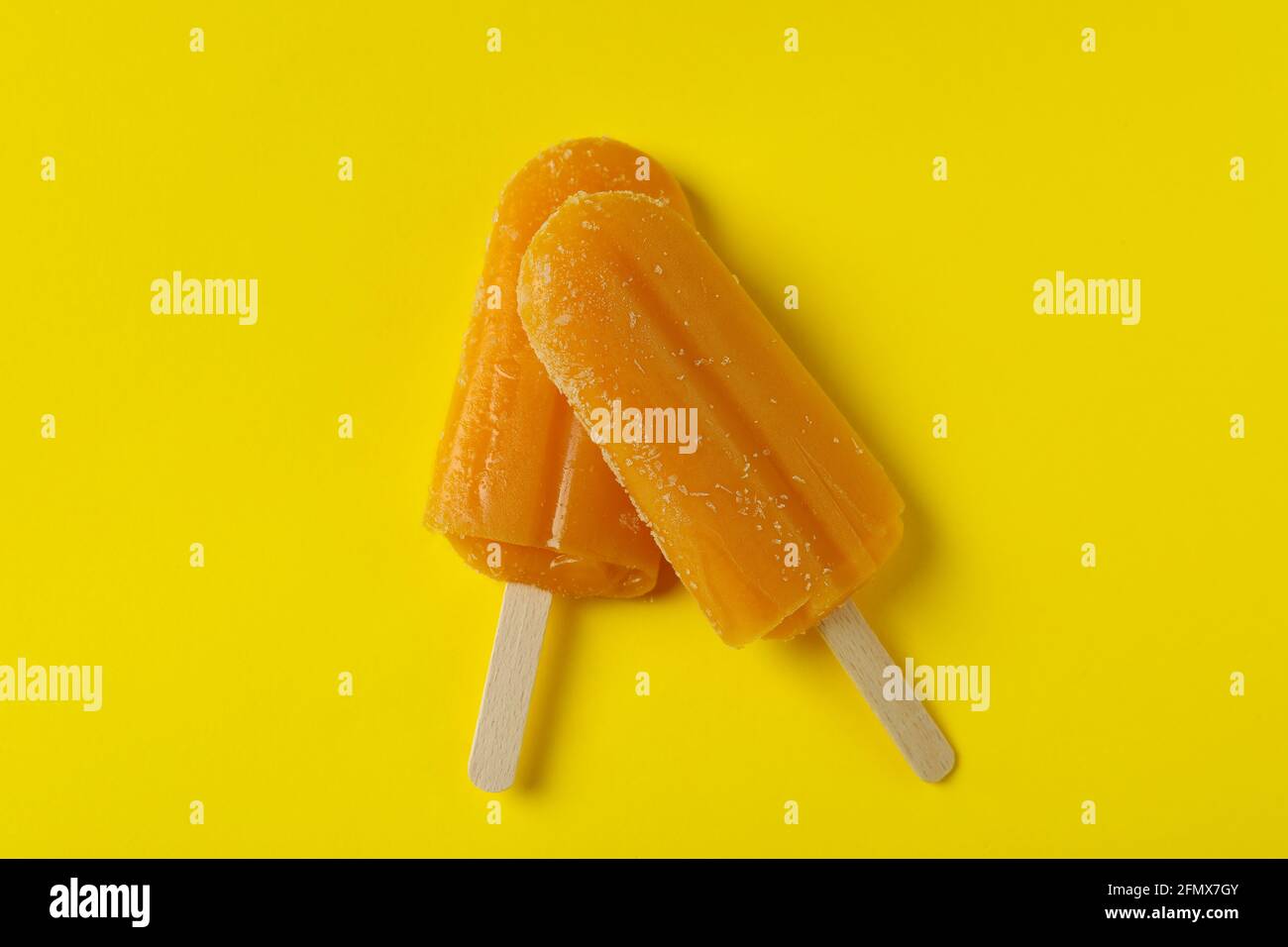 Il gelato al Mango si attacca su sfondo giallo Foto Stock