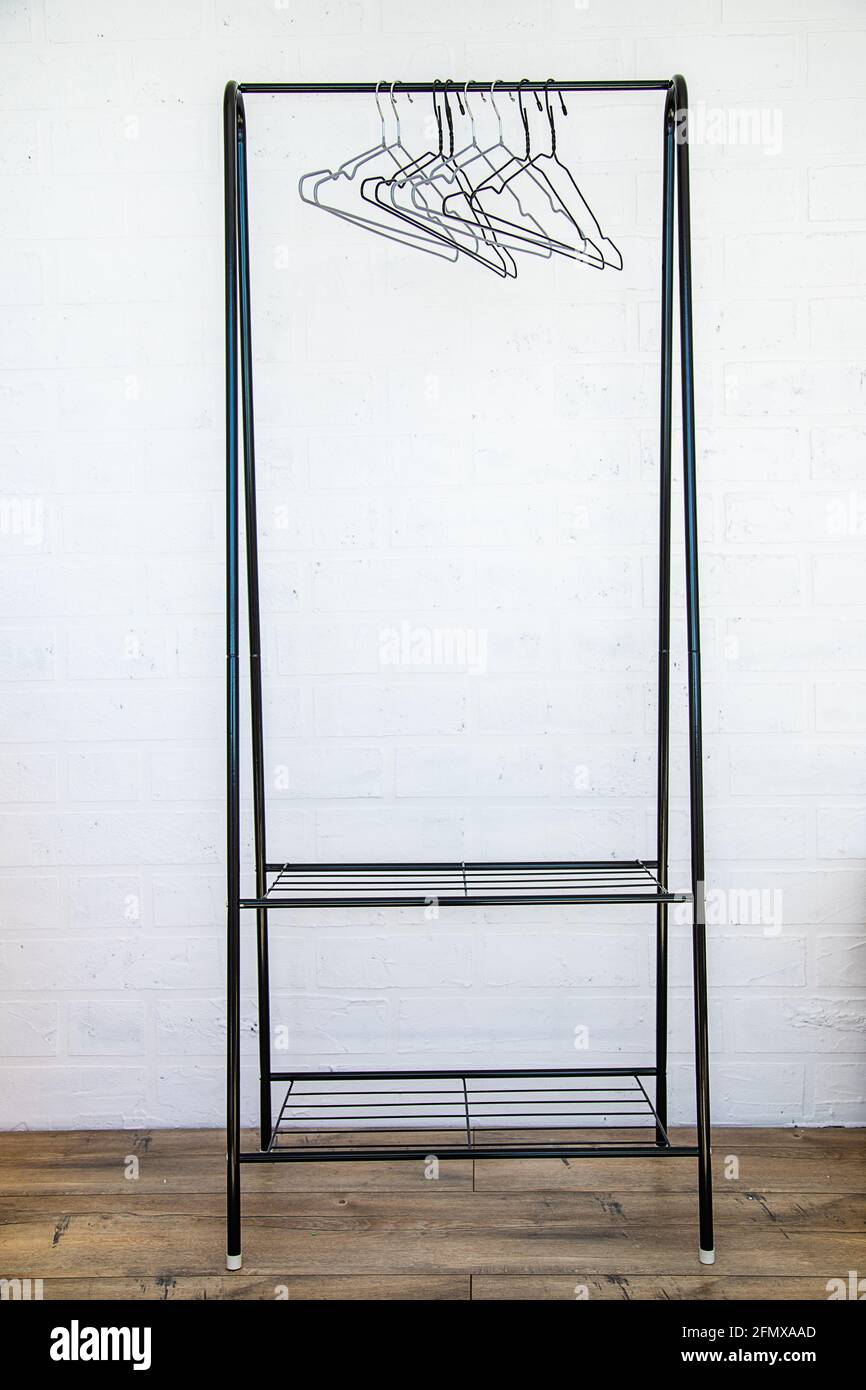 Corrimano in acciaio inox con canne vuote contro una parete bianca, pavimento in legno. Foto Stock