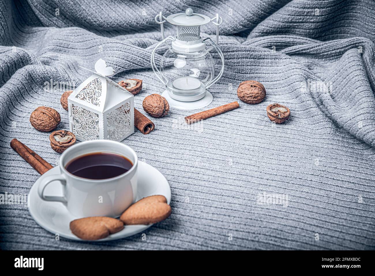 Bella plaid, una tazza con caffè e biscotti su un tavolo con candele. Foto Stock