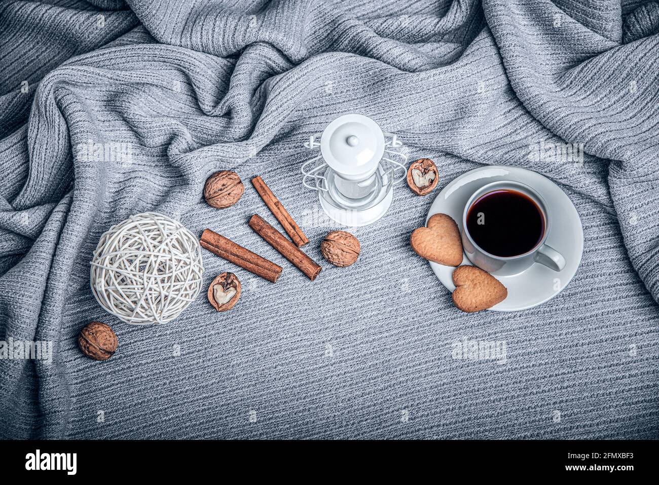 Bella plaid, una tazza con caffè e biscotti su un tavolo con candele. Foto Stock