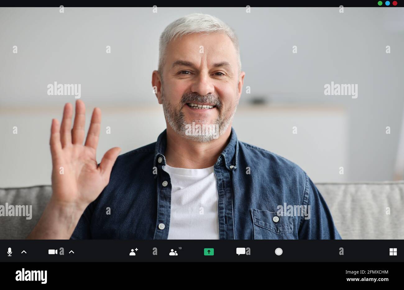 Bell'uomo anziano che ha una videoconferenza, sventolando alla telecamera Foto Stock