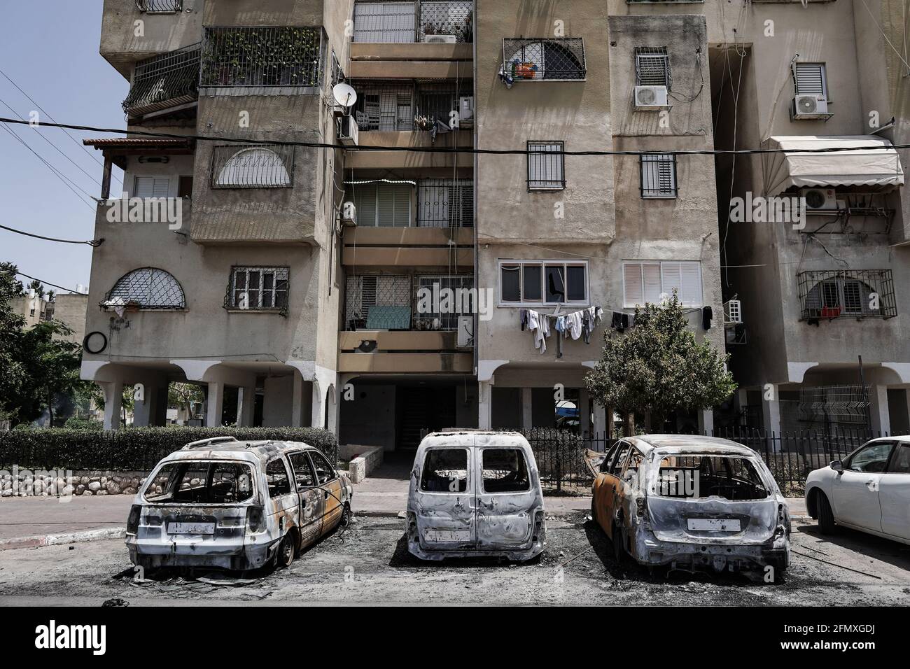 Lod, Israele. 12 maggio 2021. I detriti e i veicoli torciti costellano le strade della città araba mista ebraica di Lod a seguito di una notte di saccheggi arabi contro gli ebrei in tutto il paese in una dimostrazione di sostegno a Hamas in mezzo all’operazione militare Guardiano delle Mura di Israele a Gaza. Il conflitto militare, giunto al 3° giorno, è iniziato a seguito di un salvo di razzi lanciati dal gruppo terroristico Hamas di Gaza verso Gerusalemme. Il governo israeliano ha dichiarato uno stato di emergenza speciale a Lod conferendo alla polizia un'autorità estesa. Credit: NIR Alon/Alamy Live News Foto Stock