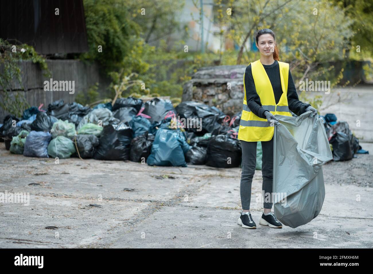 giovane donna volontaria di pulizia su parco e in piedi da mazzo di sacchetto di spazzatura Foto Stock